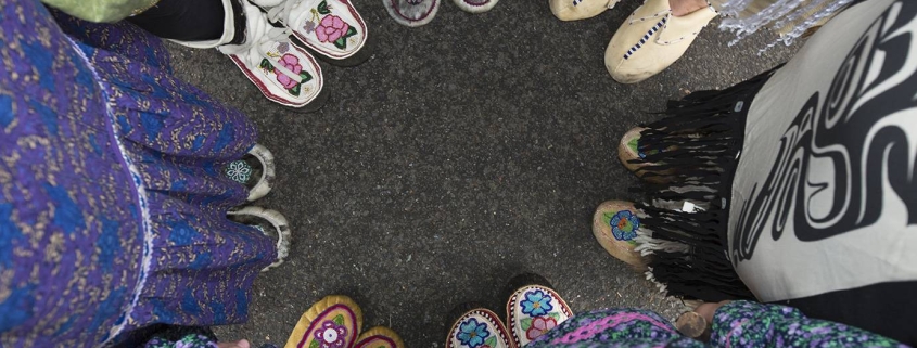 People wearing moccasins standing in a circle