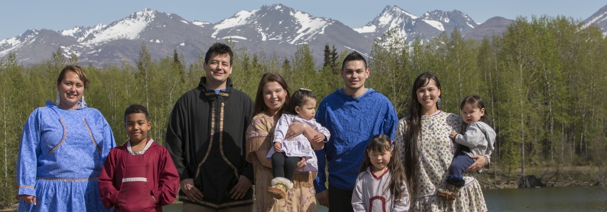 Alaska Native family posing in front of trees and mountains