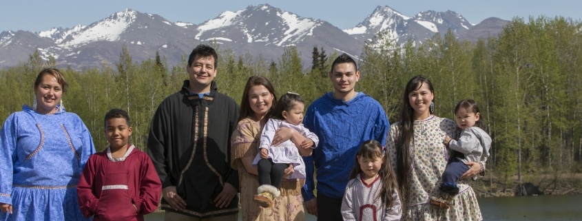 Alaska Native family posing in front of trees and mountains