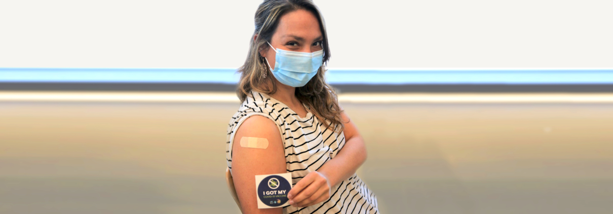Woman holding a sticker that shows she got her vaccine