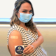 Woman holding a sticker that shows she got her vaccine